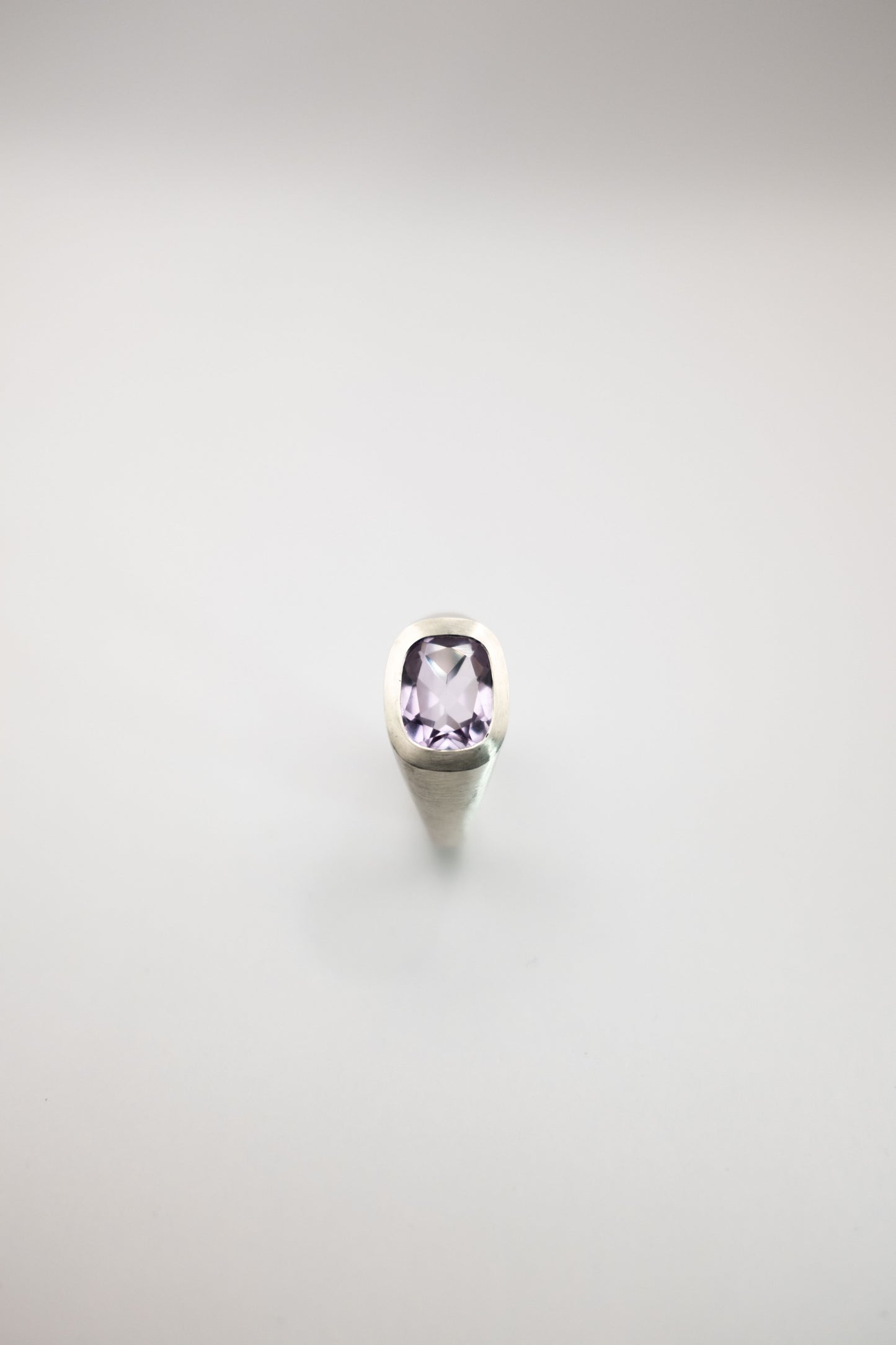 Silver ring with a purple amethyst gemstone on a white background
