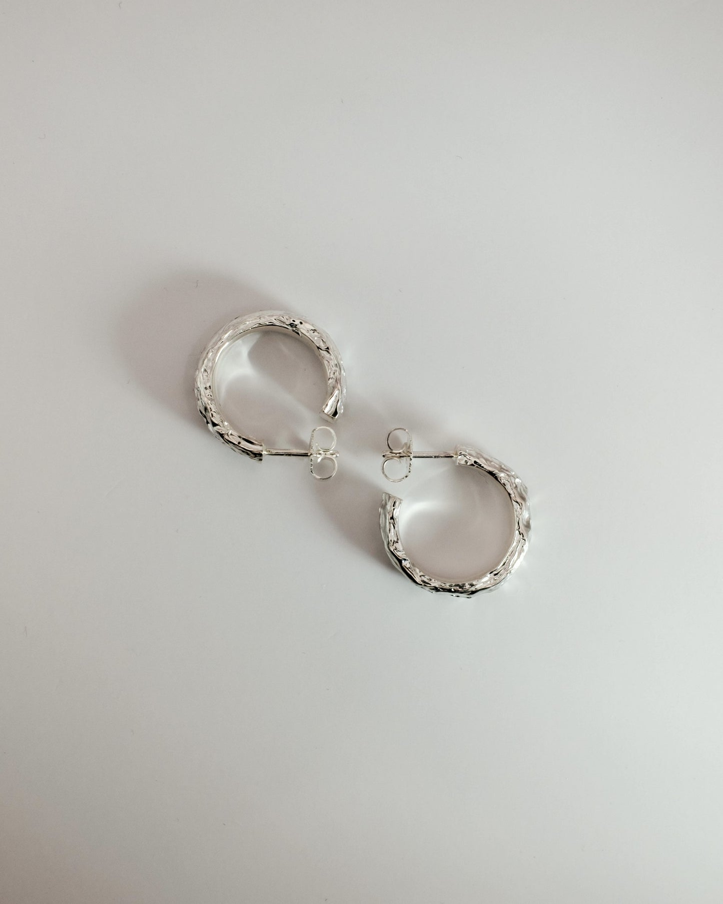 Silver hoop earrings on a light gray background