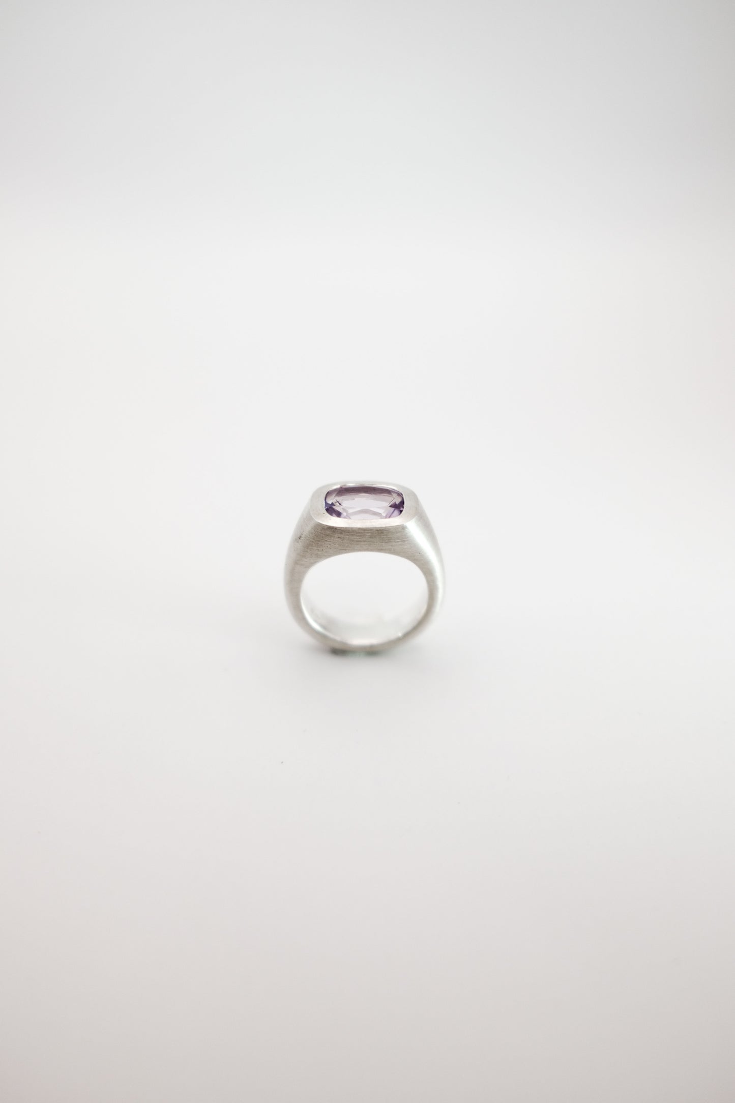 Silver ring with a pink purple gemstone on a white background