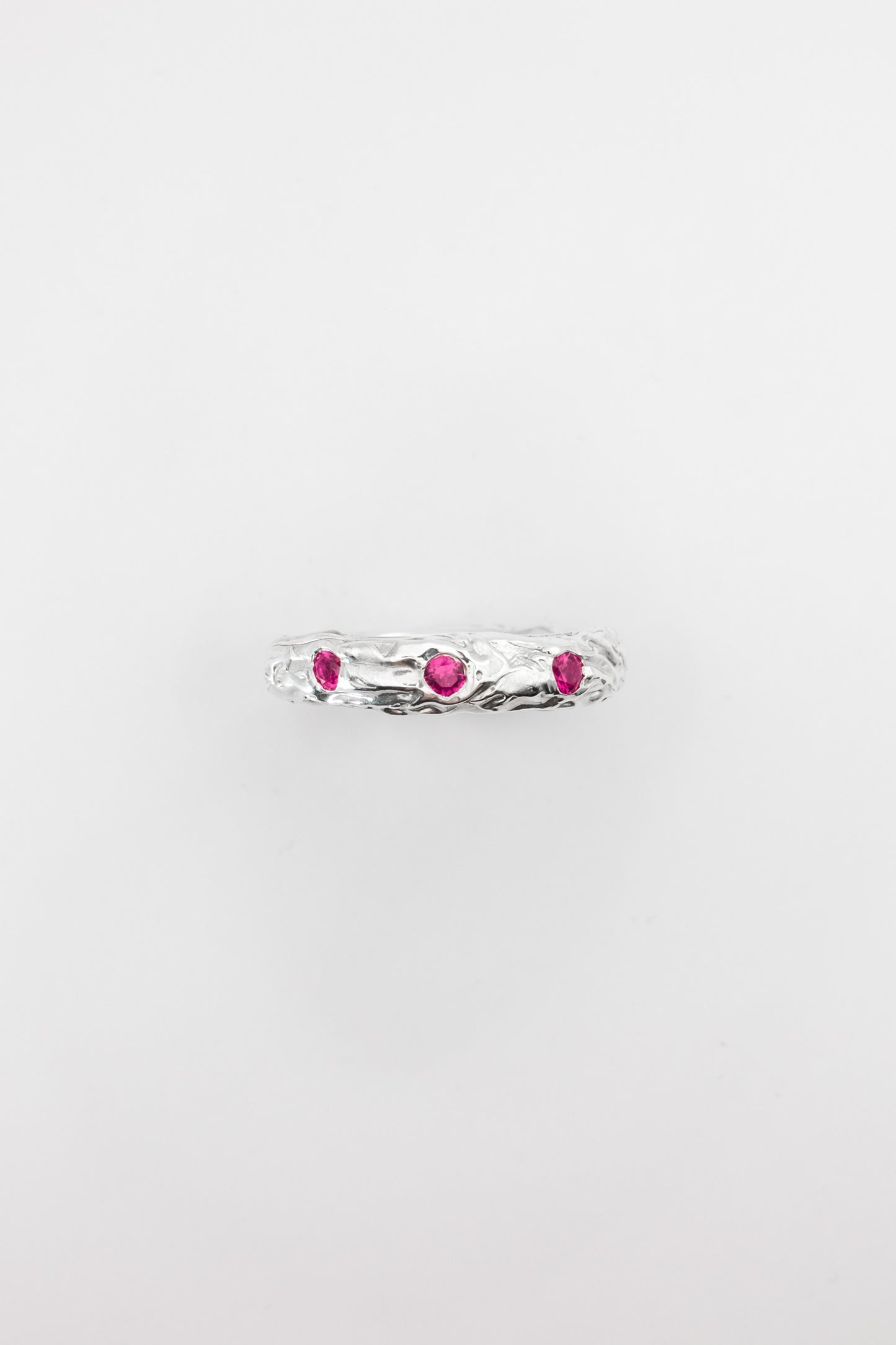 Silver ring with pink gemstones on a light gray background