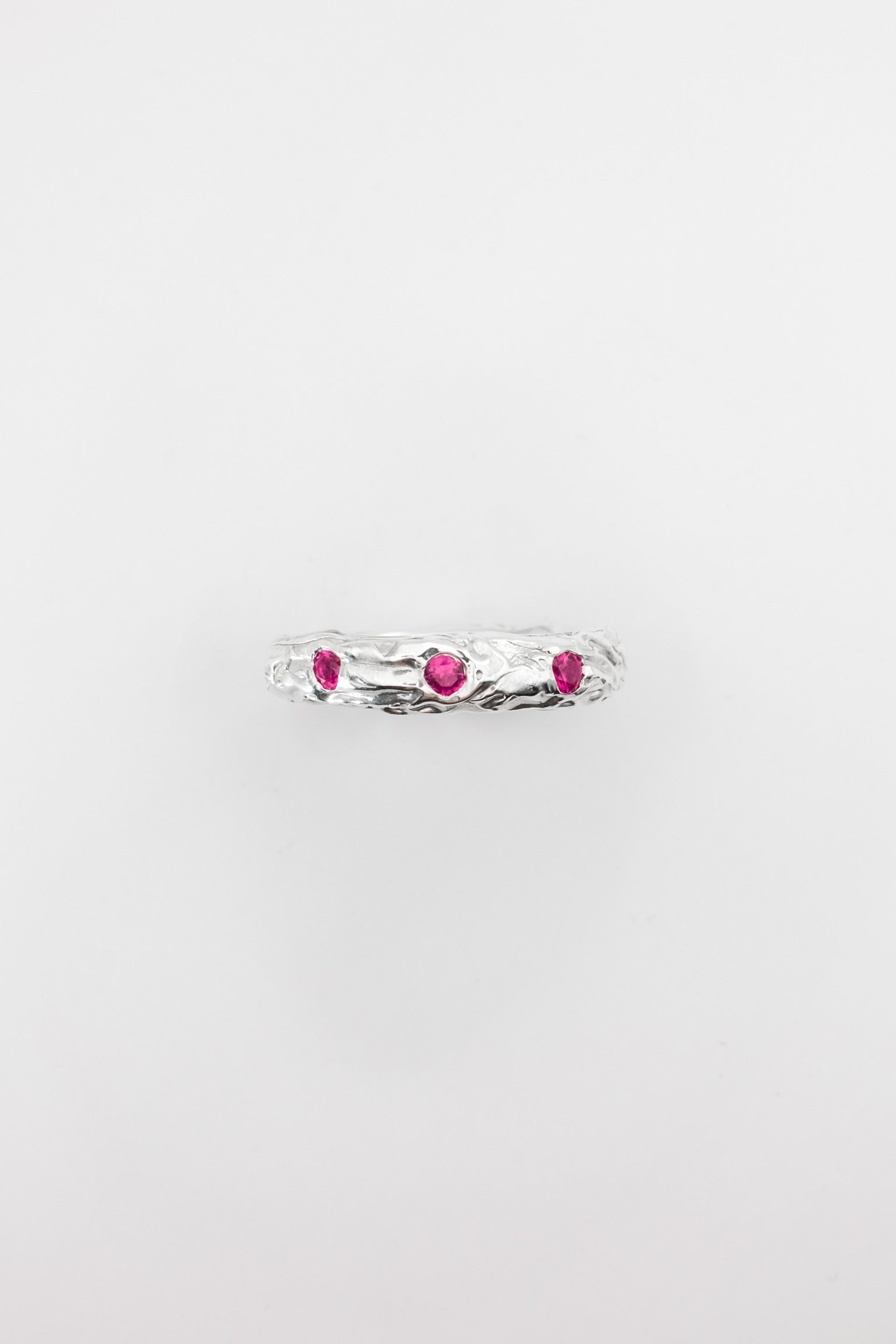 Silver ring with pink gemstones on a light gray background