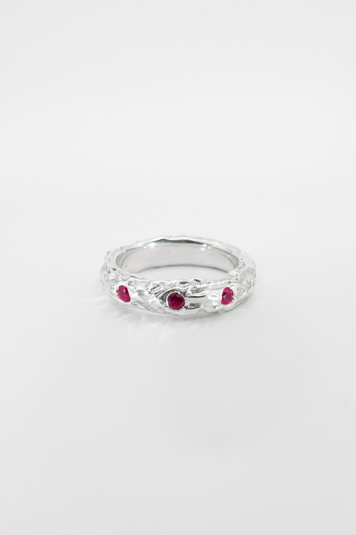 Silver ring with red gemstones on a white background