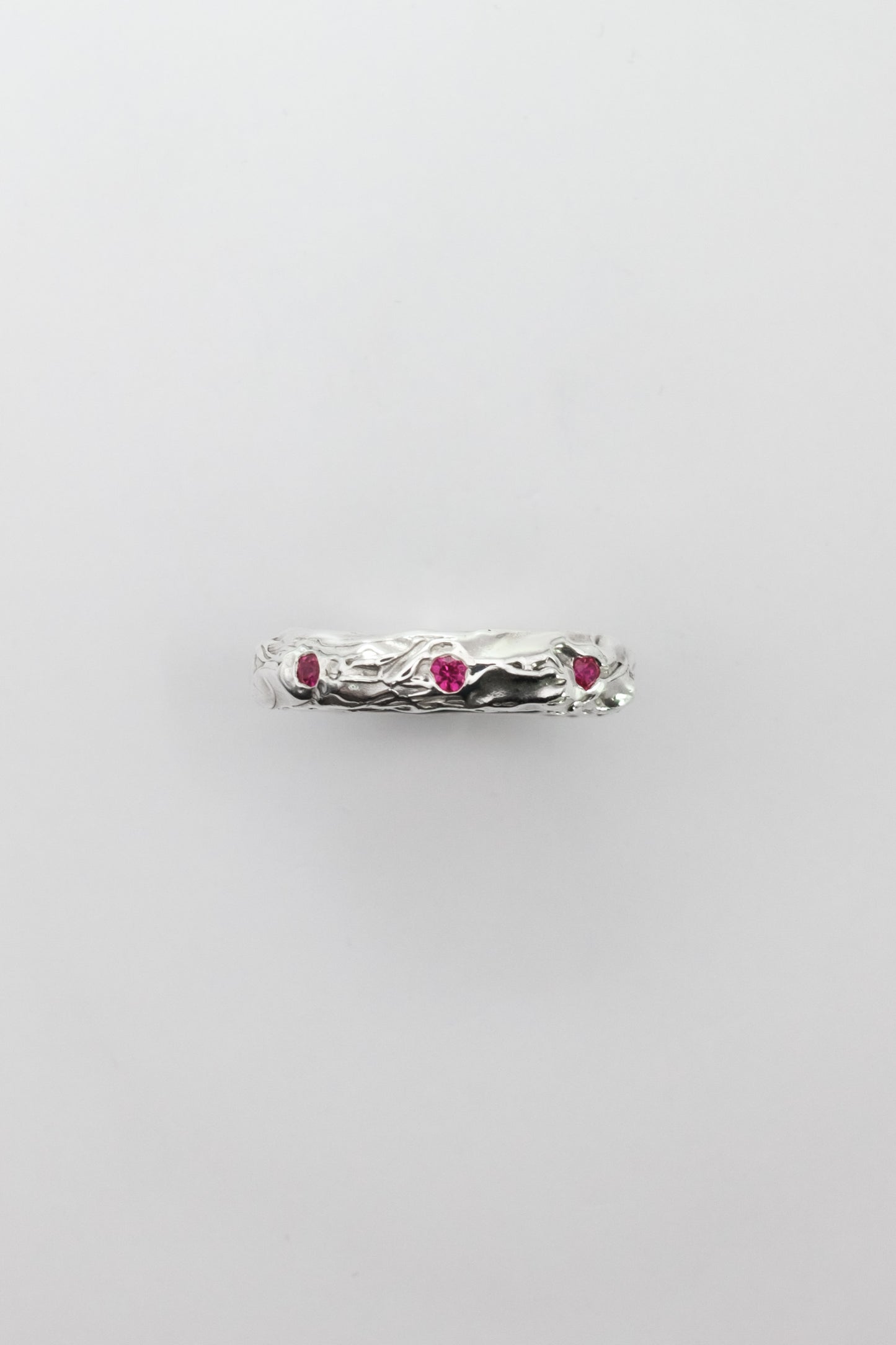 Silver ring with red gemstones on a light gray background