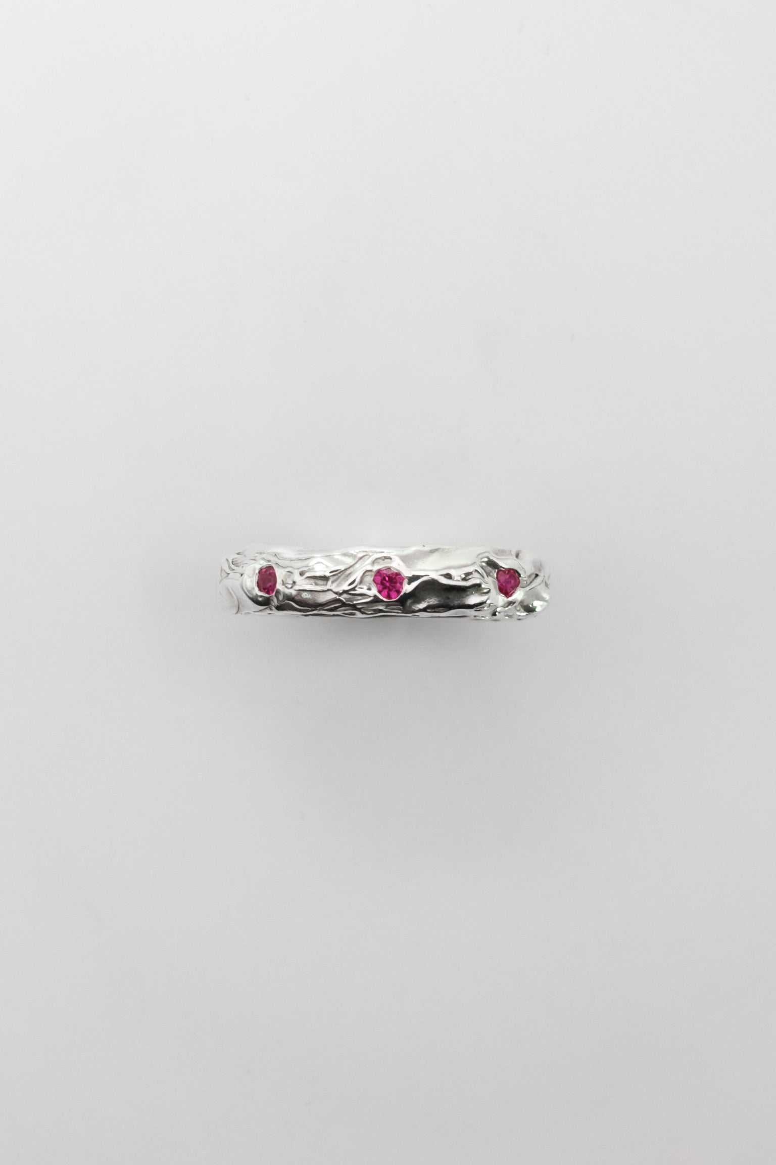 Silver ring with red gemstones on a light gray background
