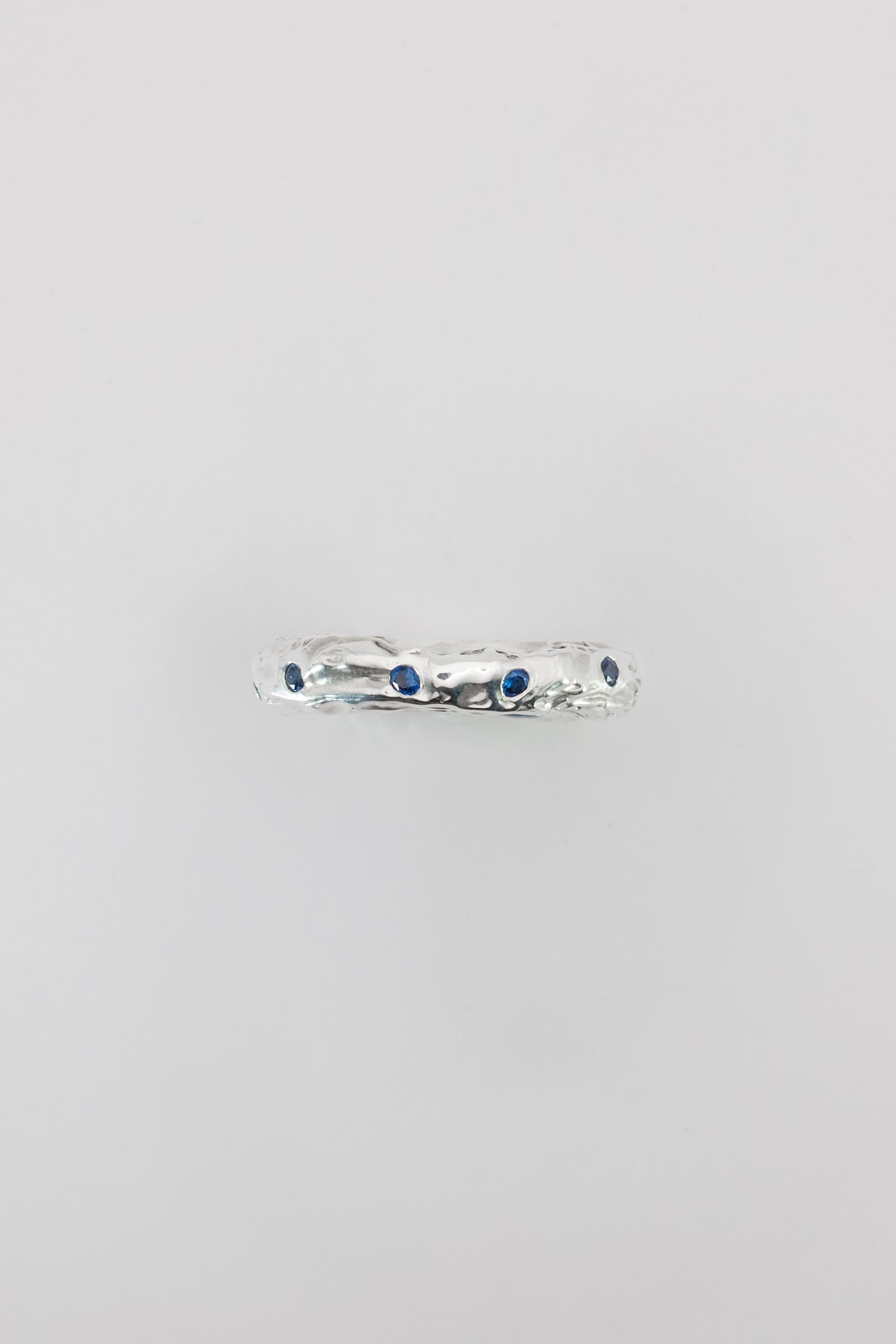 Silver ring with blue stones on a light gray background