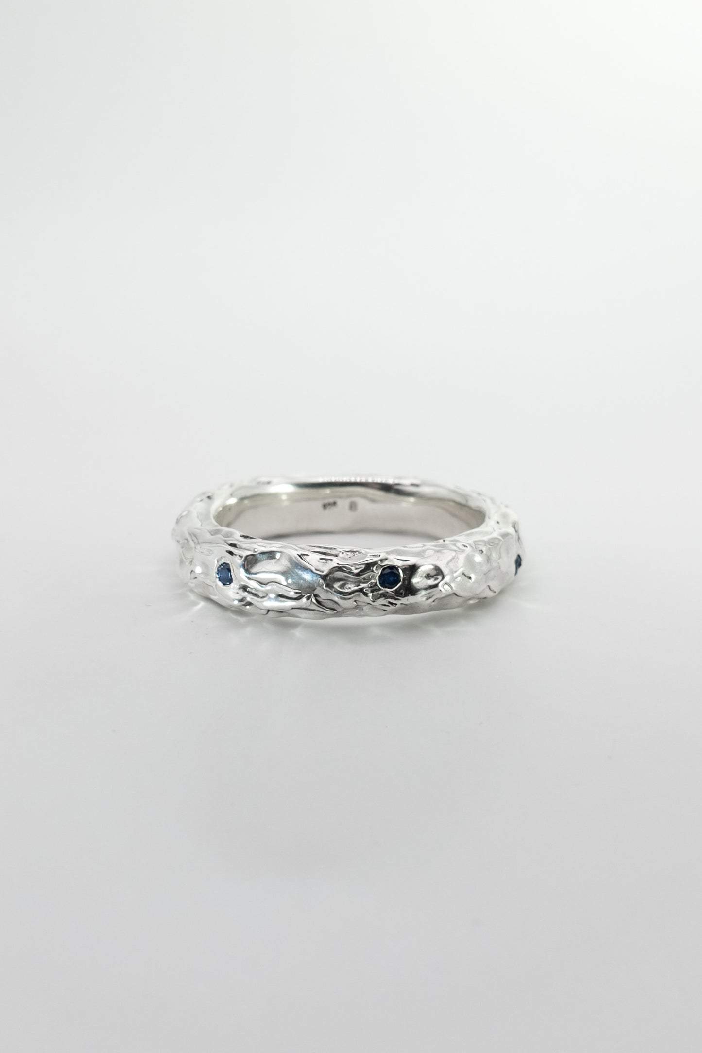 Silver ring with embedded stones on a light gray background