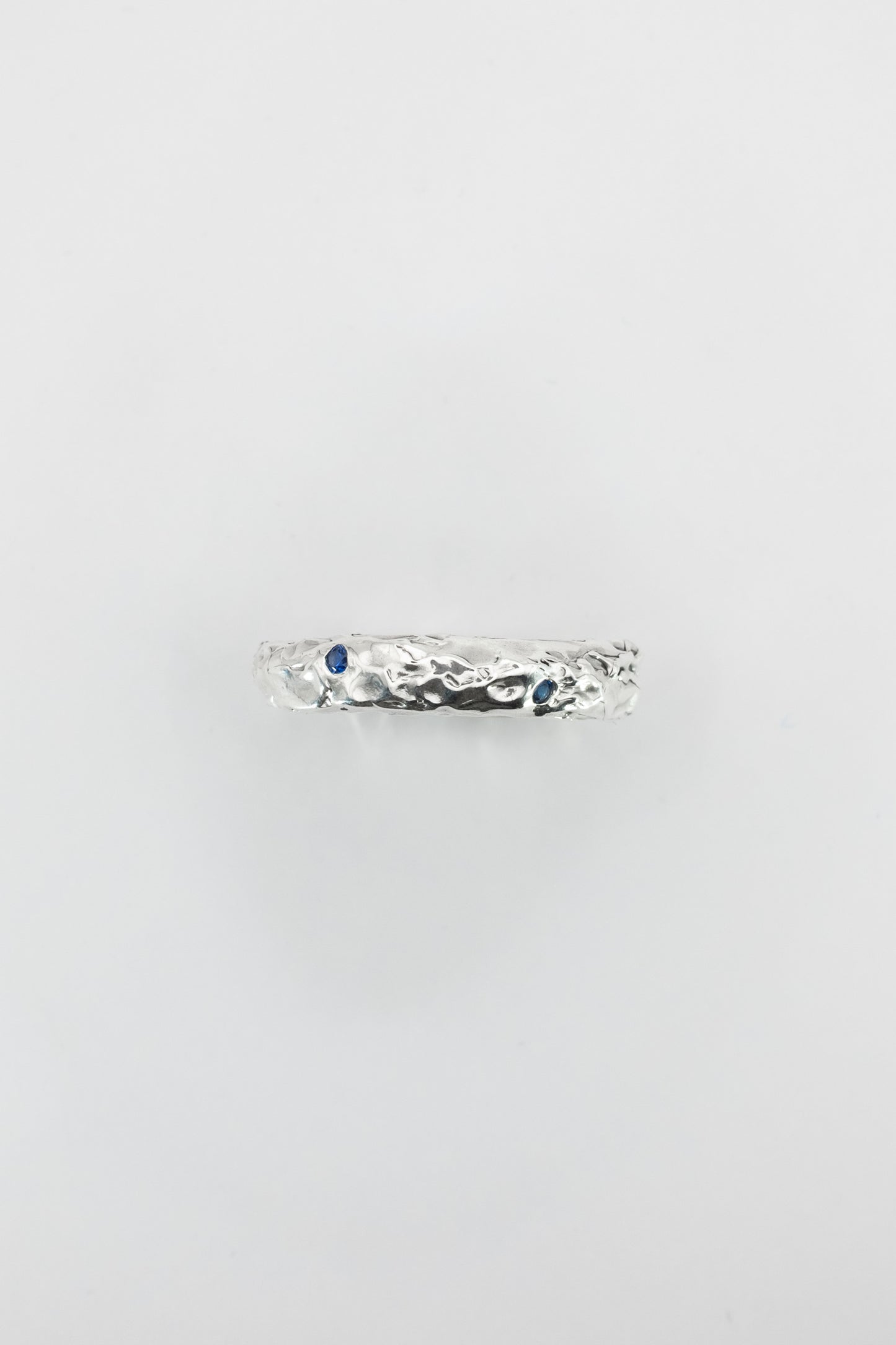 Silver ring with blue gemstones on a light gray background