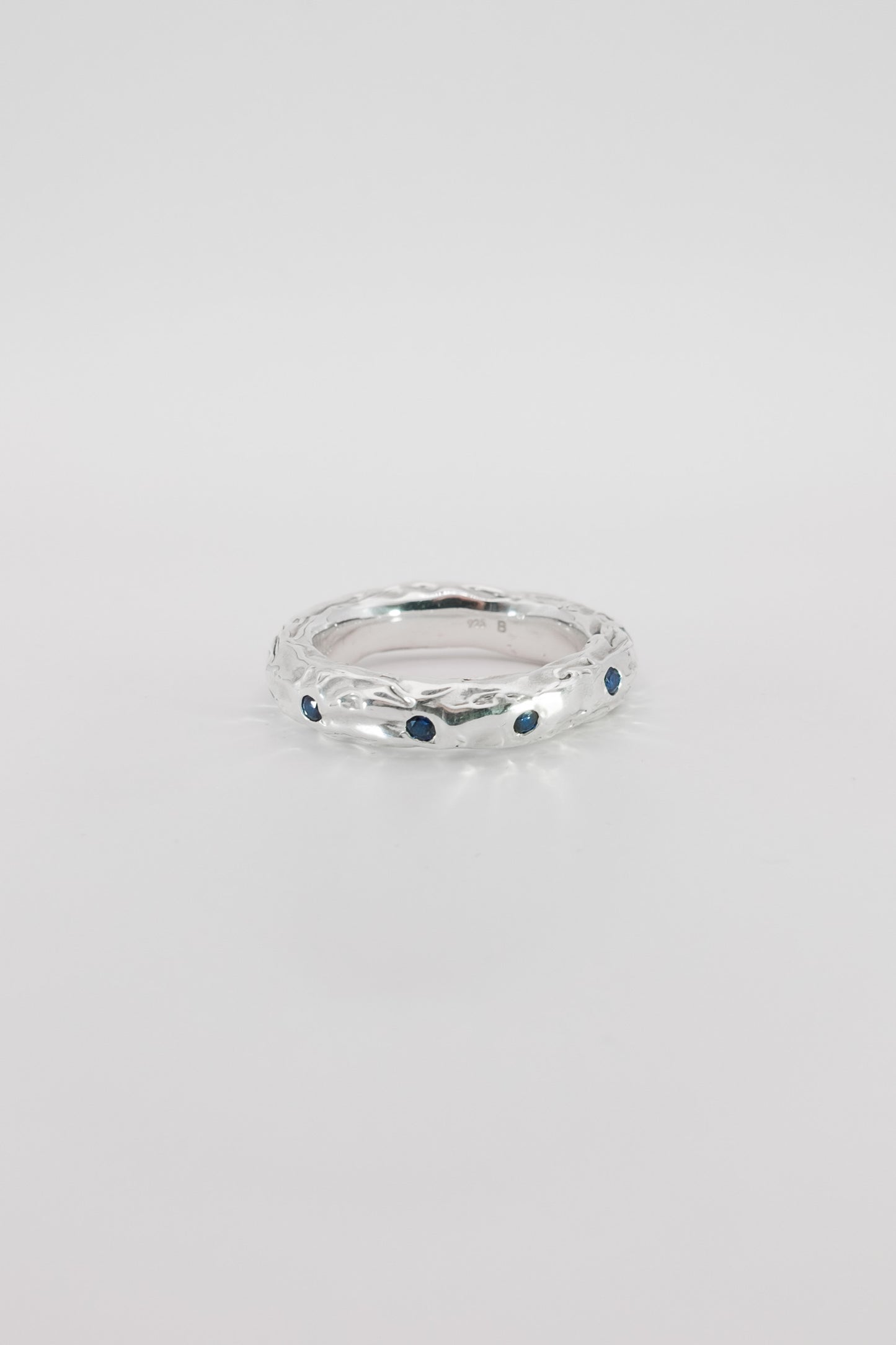 Silver ring with blue stones on a light gray background