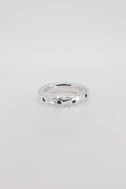 Silver ring with blue stones on a light gray background