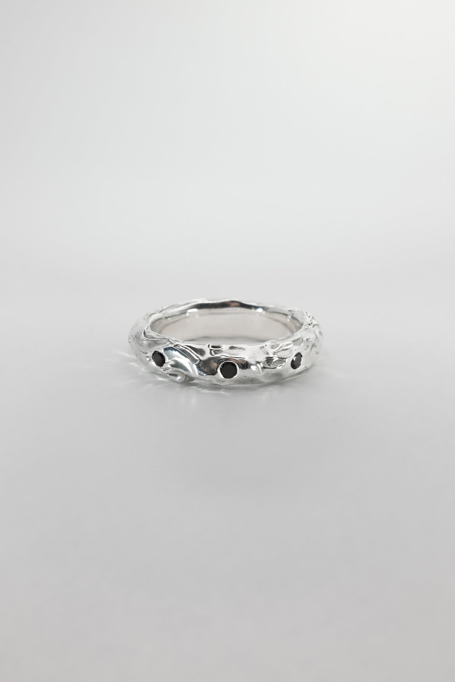 Silver ring with black stones on a light gray background