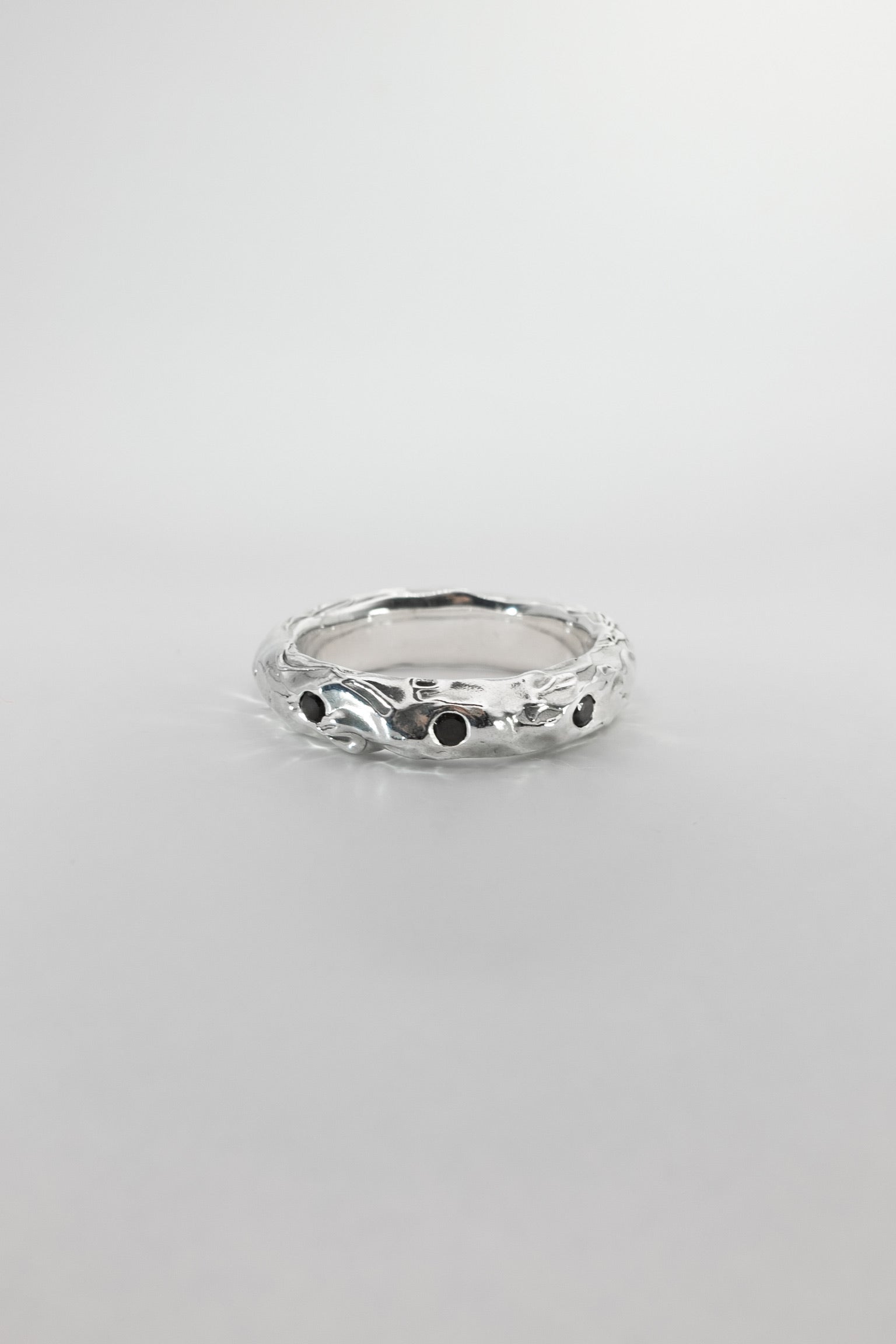 Silver ring with black stones on a light gray background