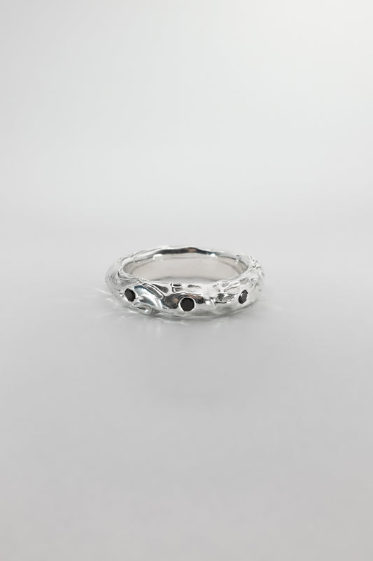 Silver ring with black stones on a light gray background