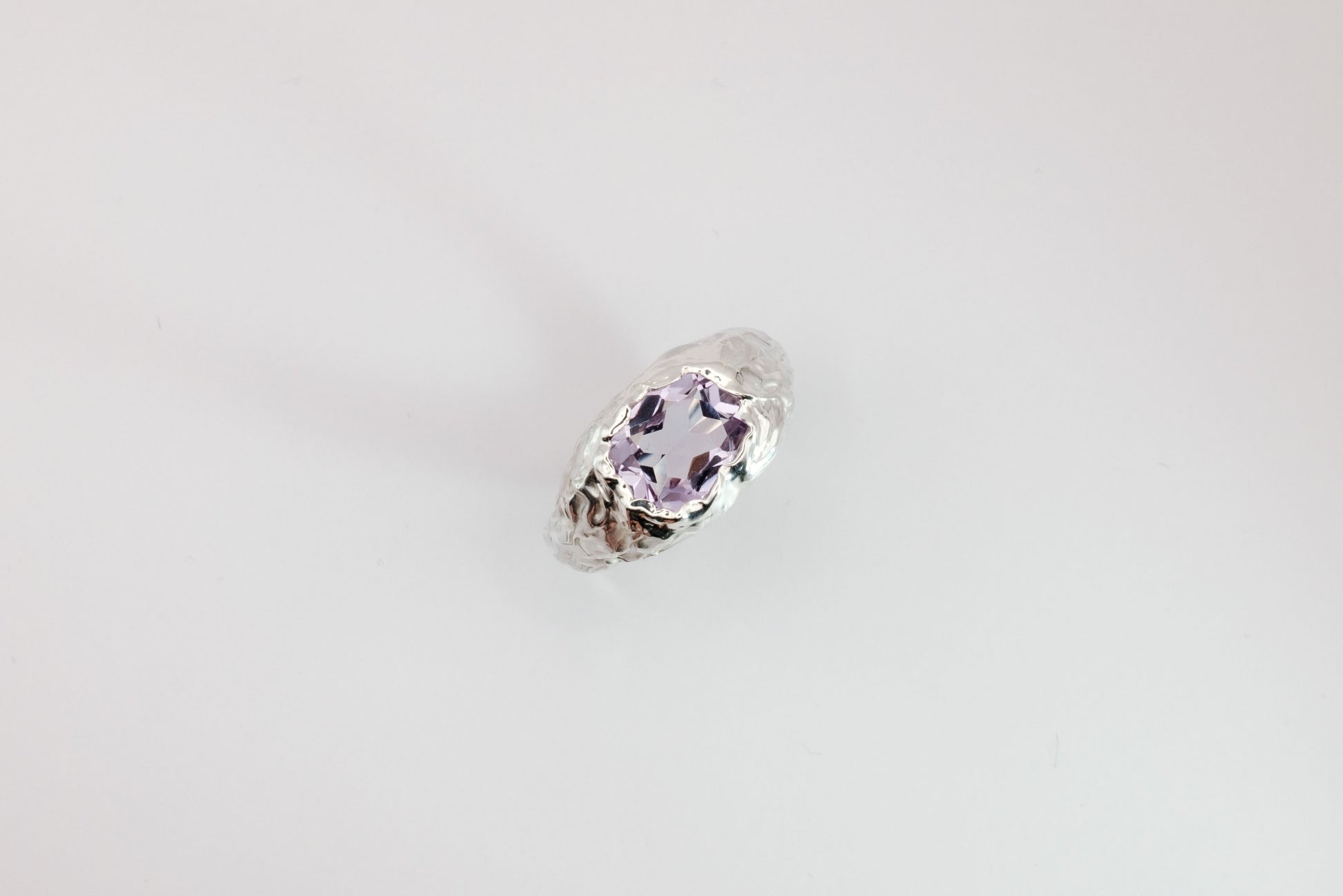 Silver ring with a pink ammethyst gemstone on a light gray background