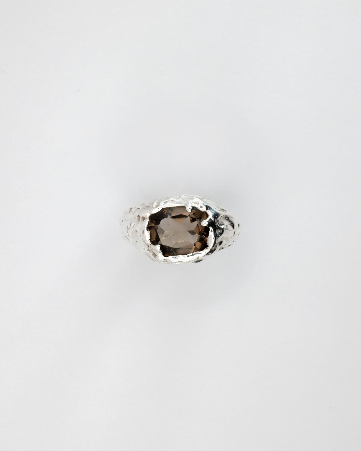 Smoky quartz gemstone in a silver setting on a light gray background