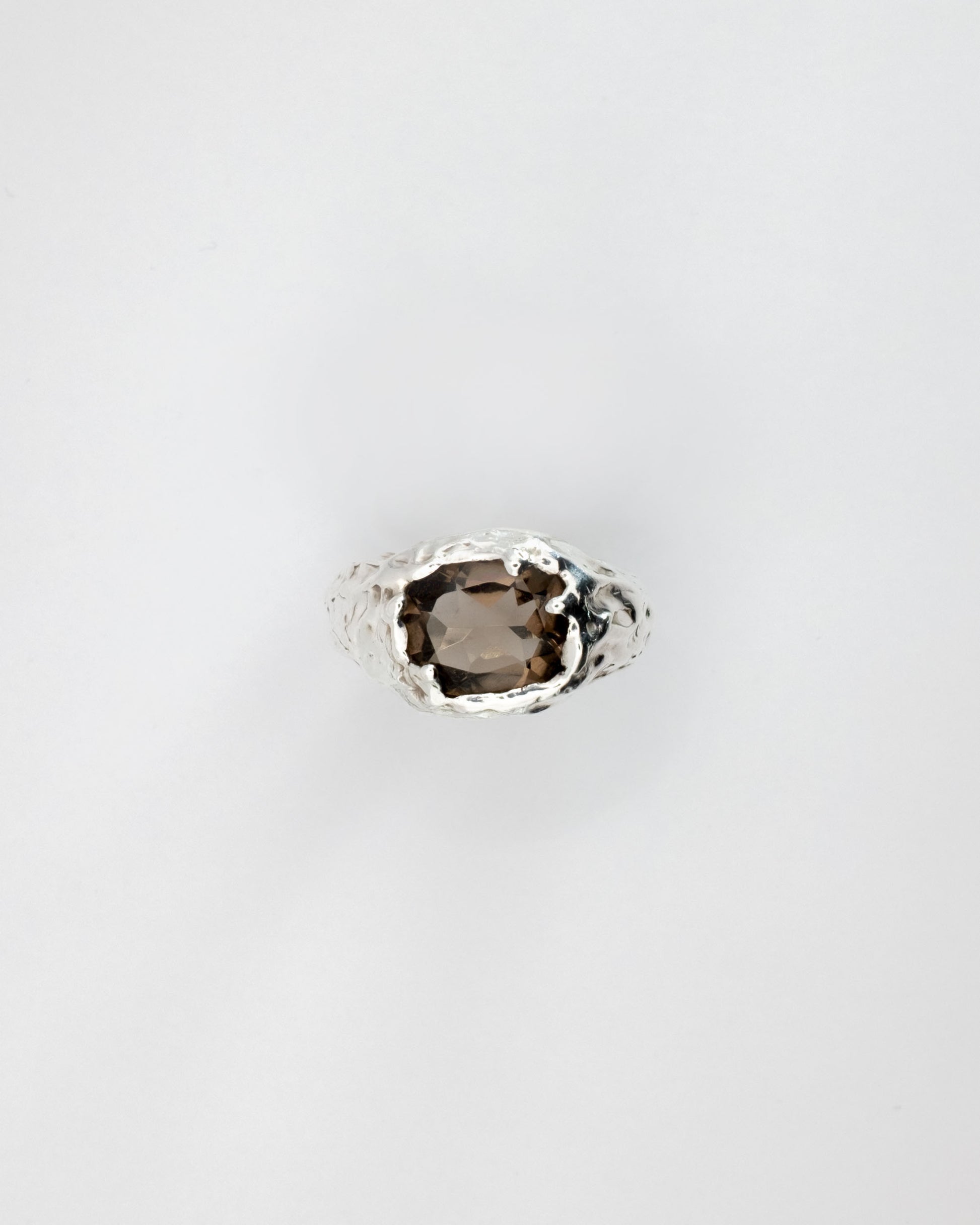 Smoky quartz gemstone in a silver setting on a light gray background
