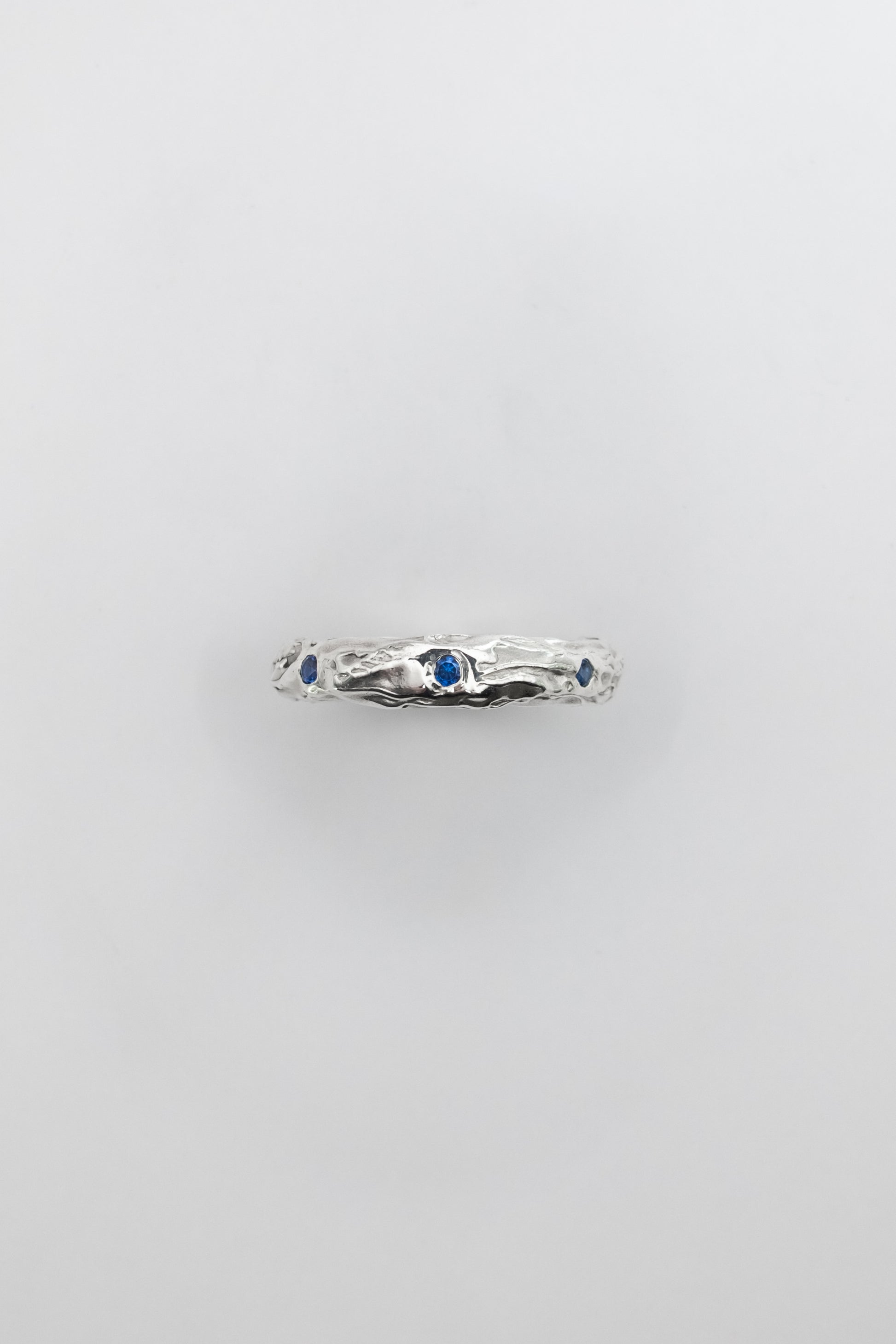 Silver ring with blue gemstones on a light gray background