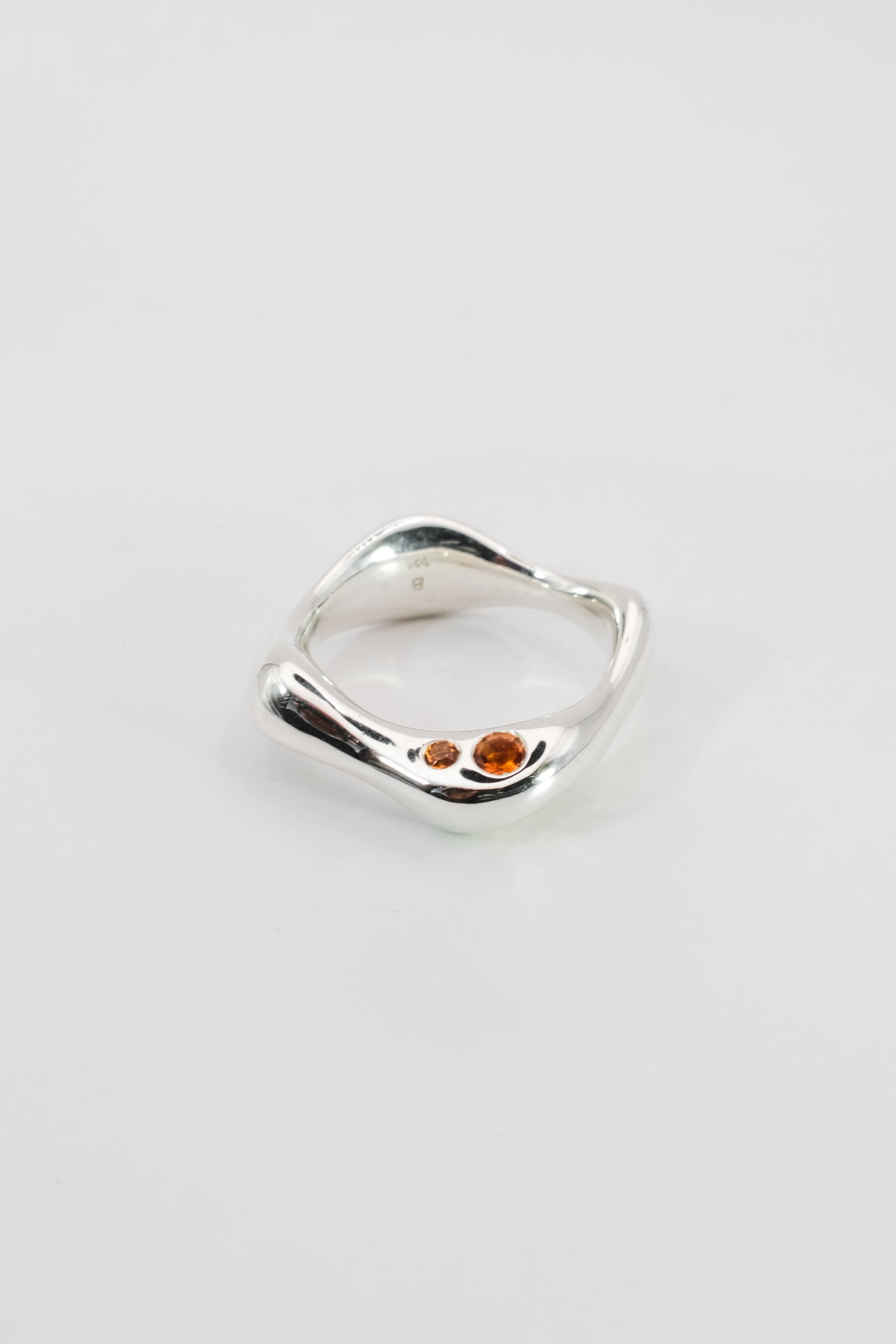 Smoothly shaped organic Silver ring with embedded Madeira Citrine gemstones on a light gray background