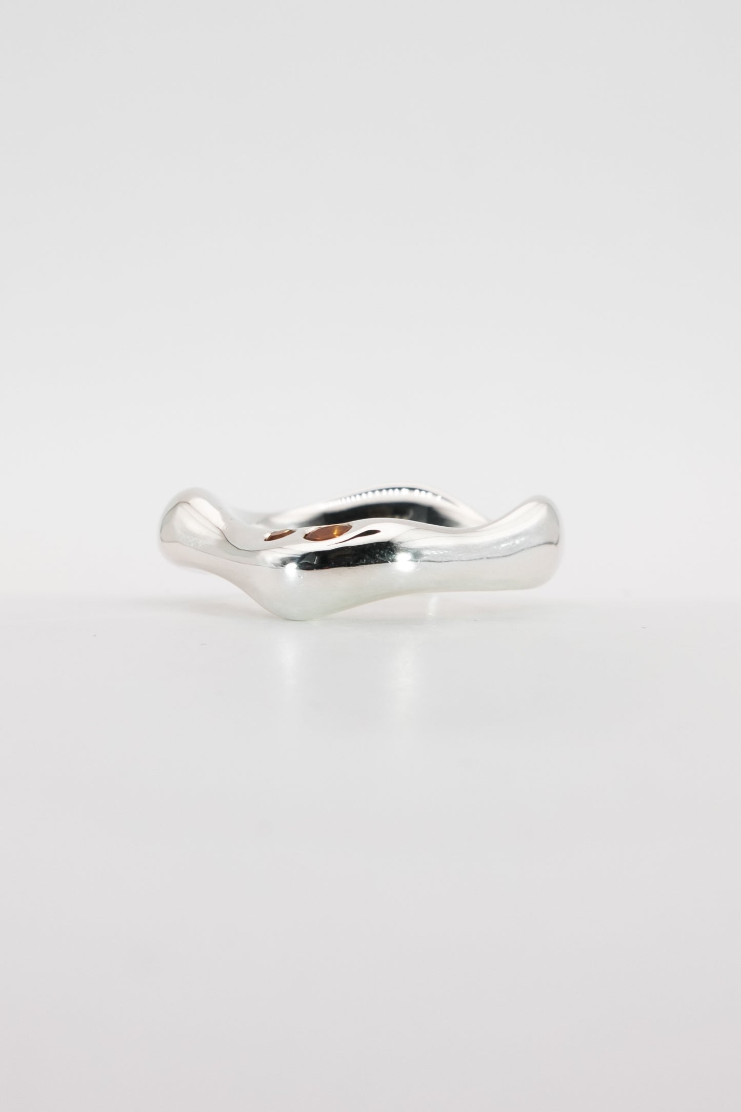 Silver ring with a wavy design on a light gray background