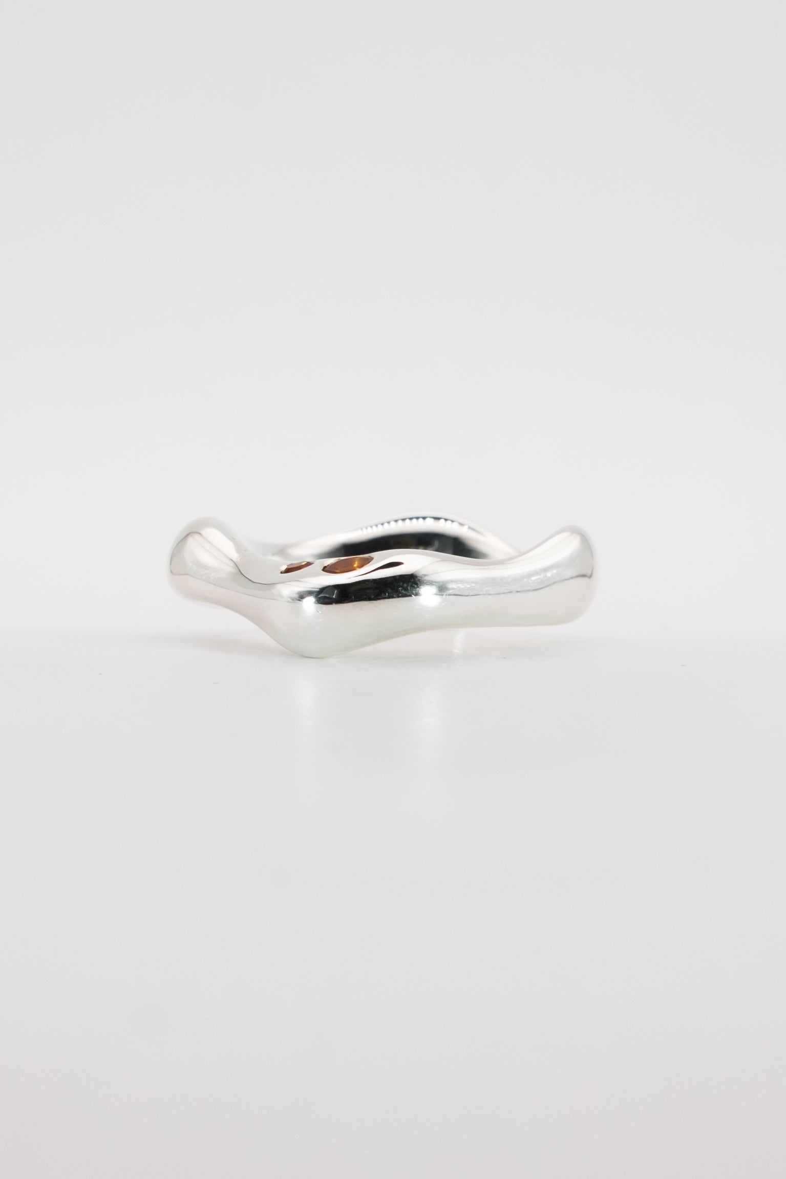 Silver ring with a wavy design on a light gray background