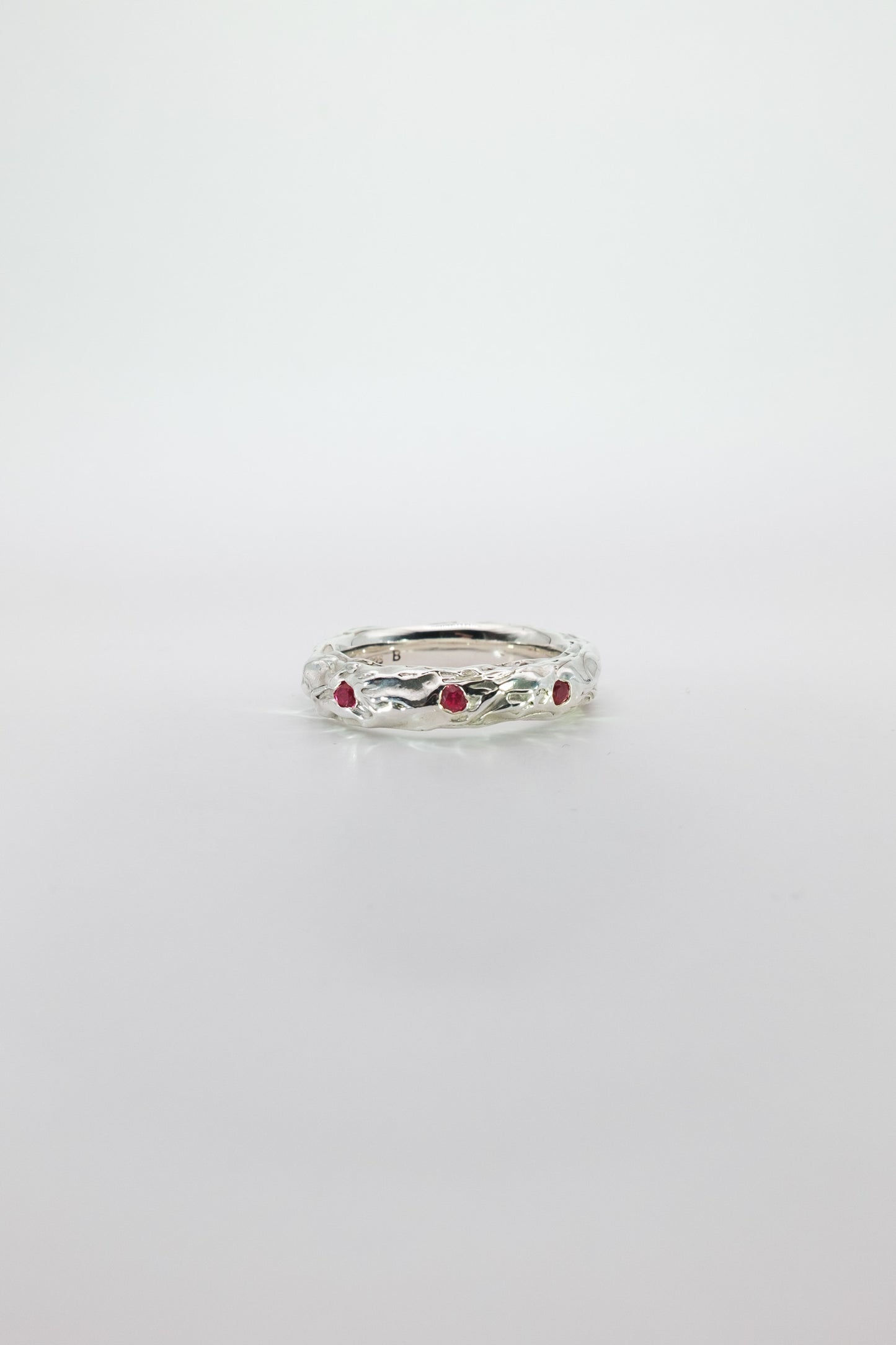 Silver ring with red rubies on a white background