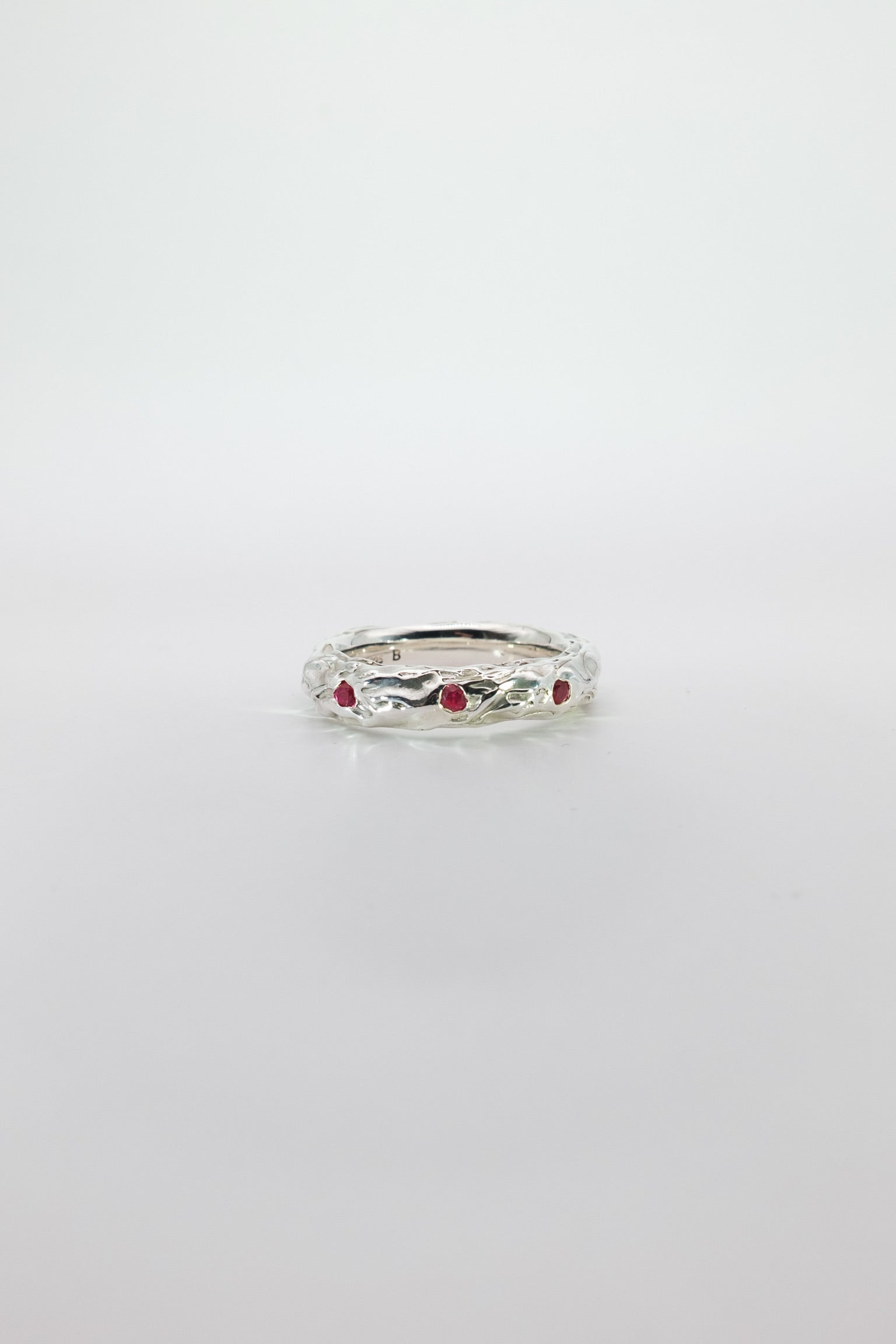 Silver ring with red rubies on a white background