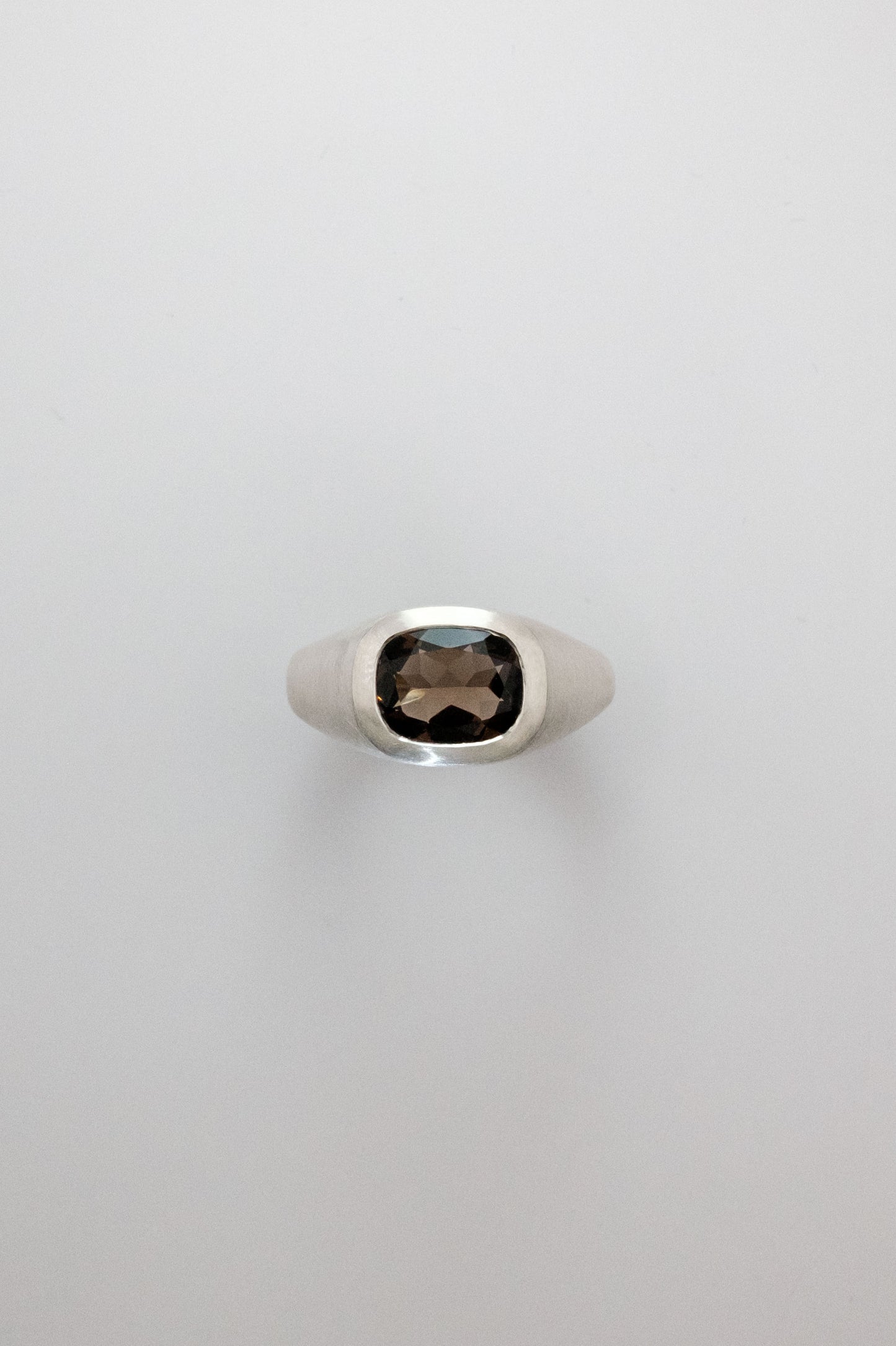Silver ring with a smoky gemstone on a light gray background