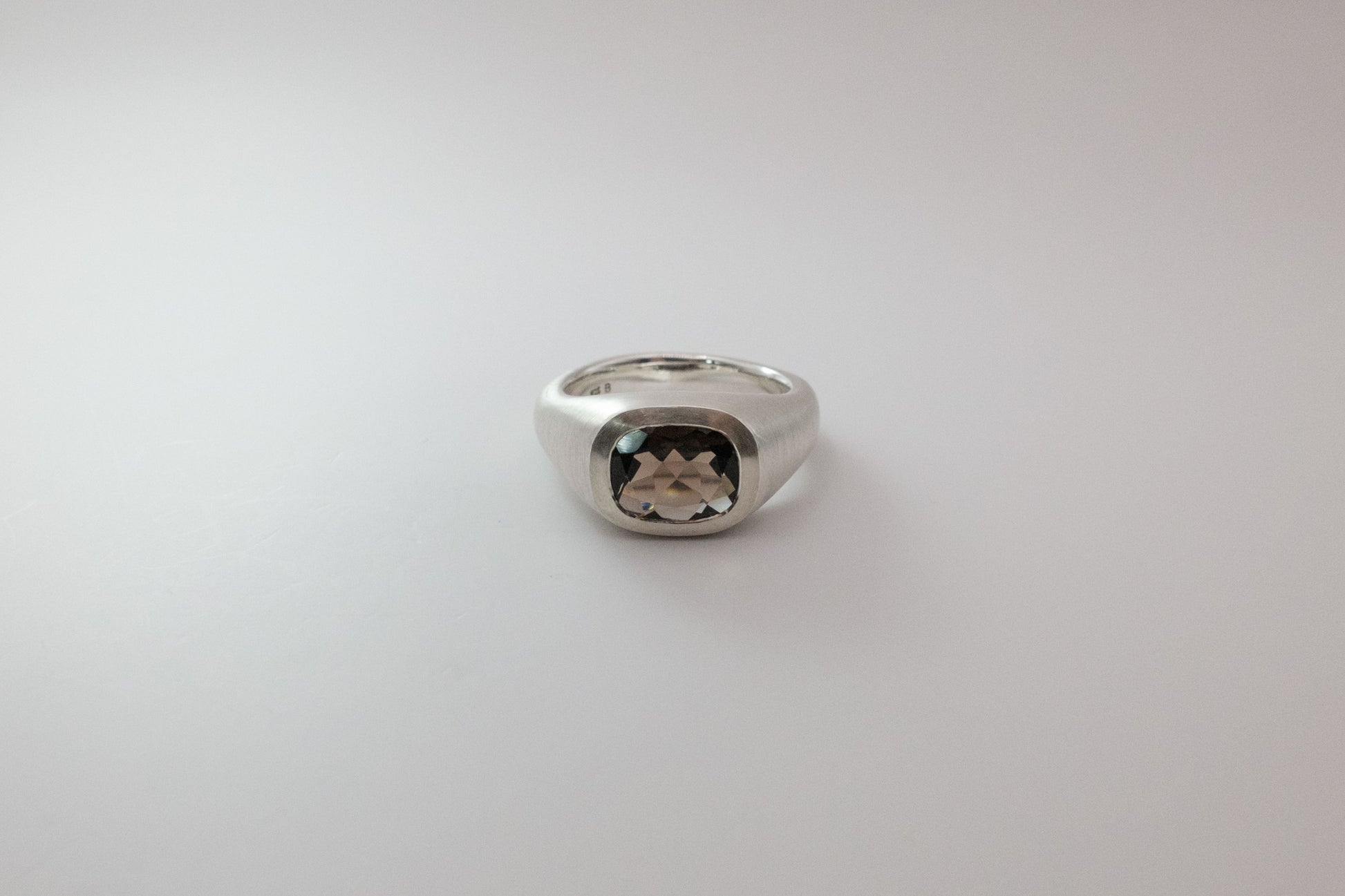 Silver ring with a gemstone on a light gray background