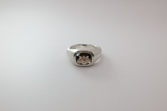 Silver ring with a gemstone on a light gray background