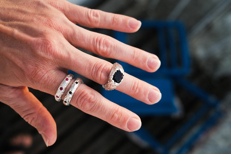 Hand wearing multiple bespoke rings with a blurred background