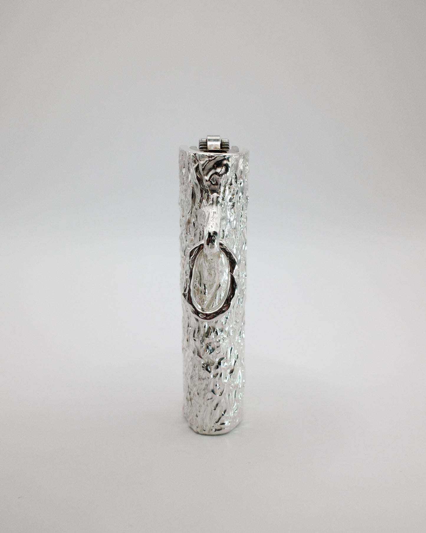 Silver lighter case with textured surface on a light gray background