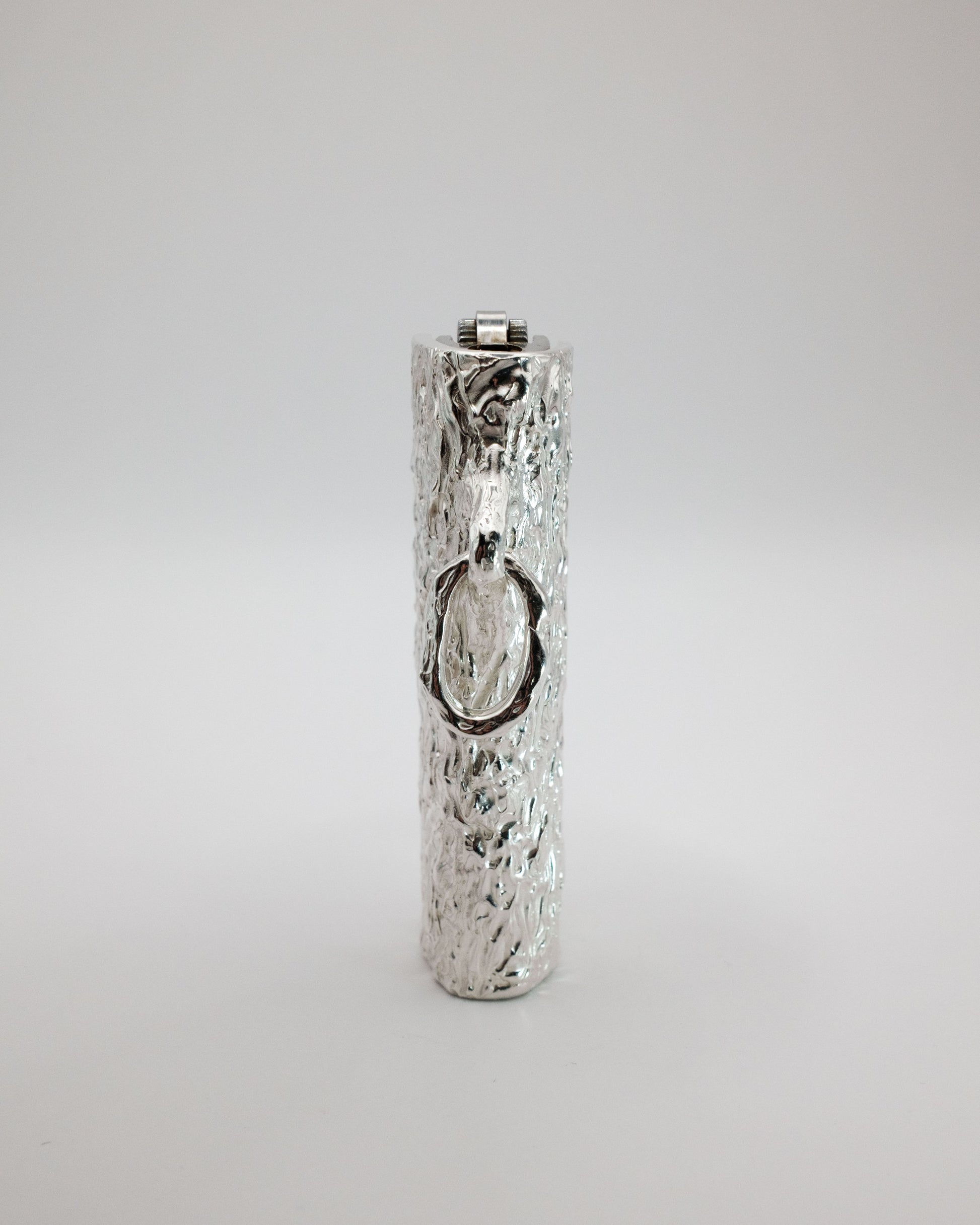 Silver lighter case with textured surface on a light gray background