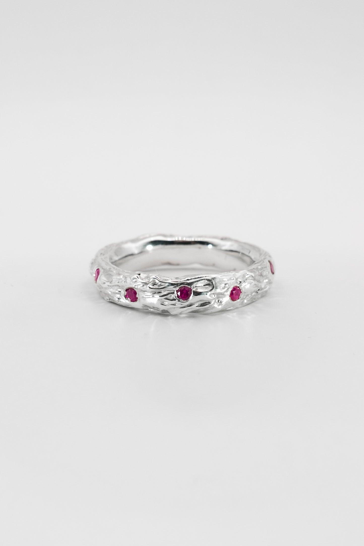 Silver ring with red gemstones on a white background