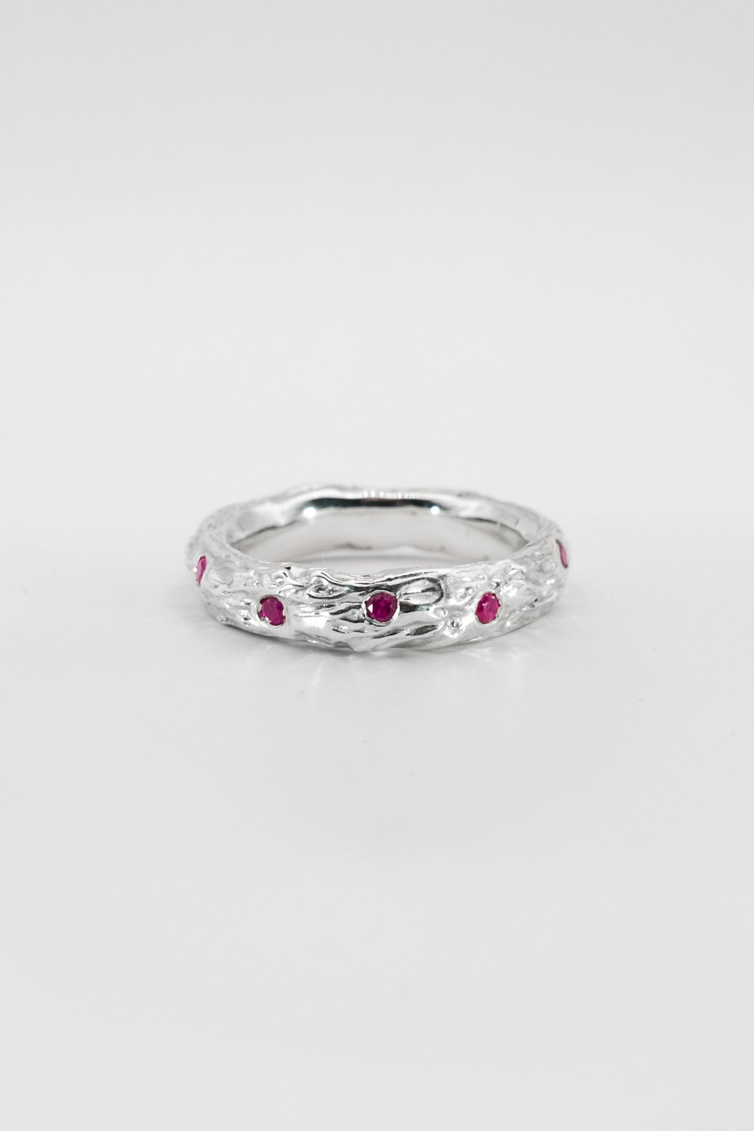 Silver ring with red gemstones on a white background