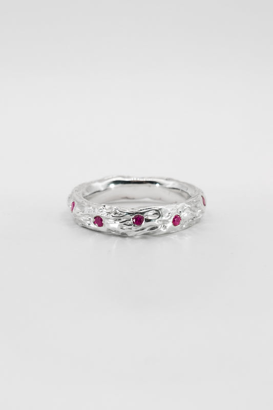 Silver ring with red gemstones on a white background