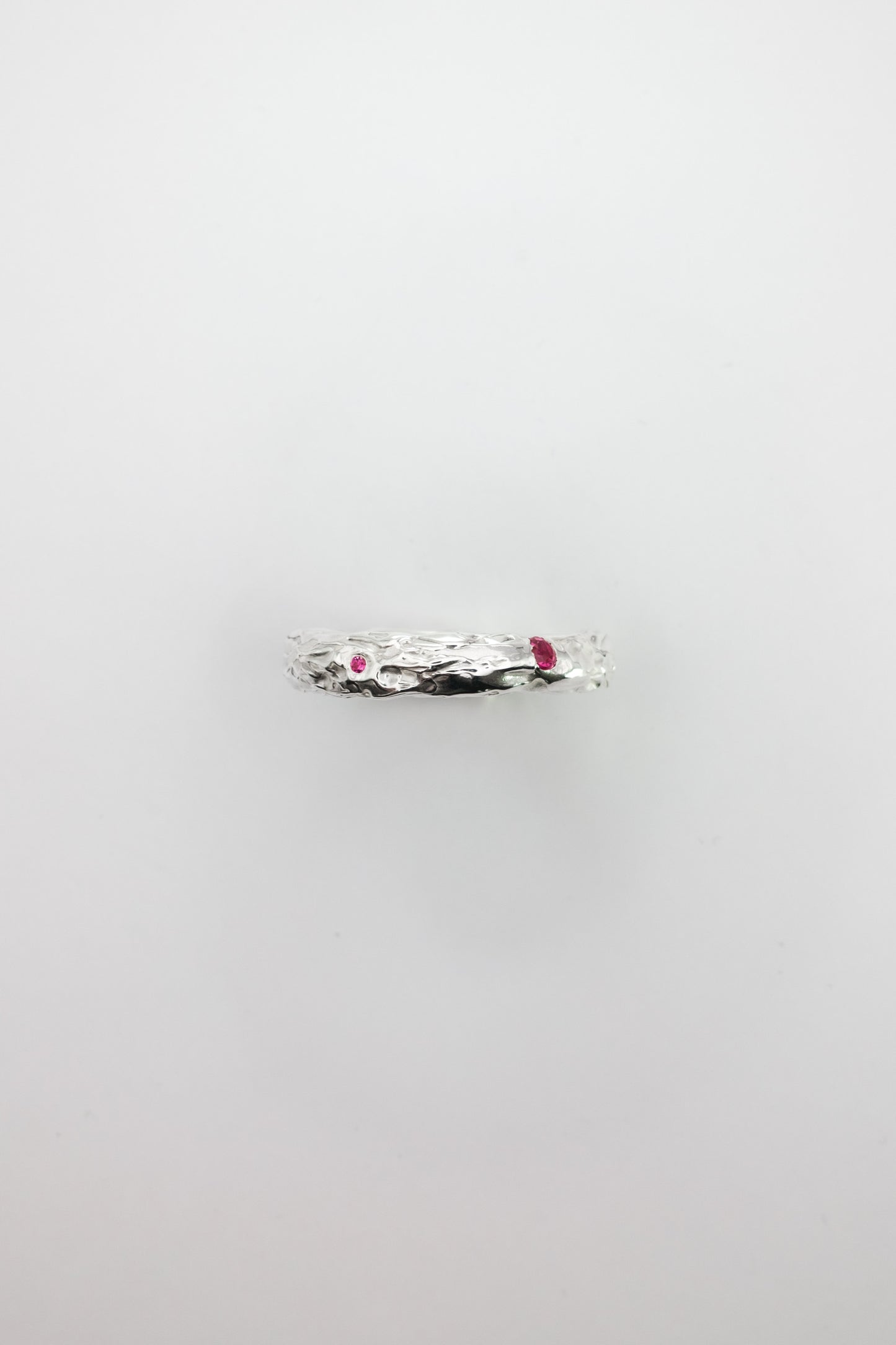 Silver ring with red stones on a light gray background