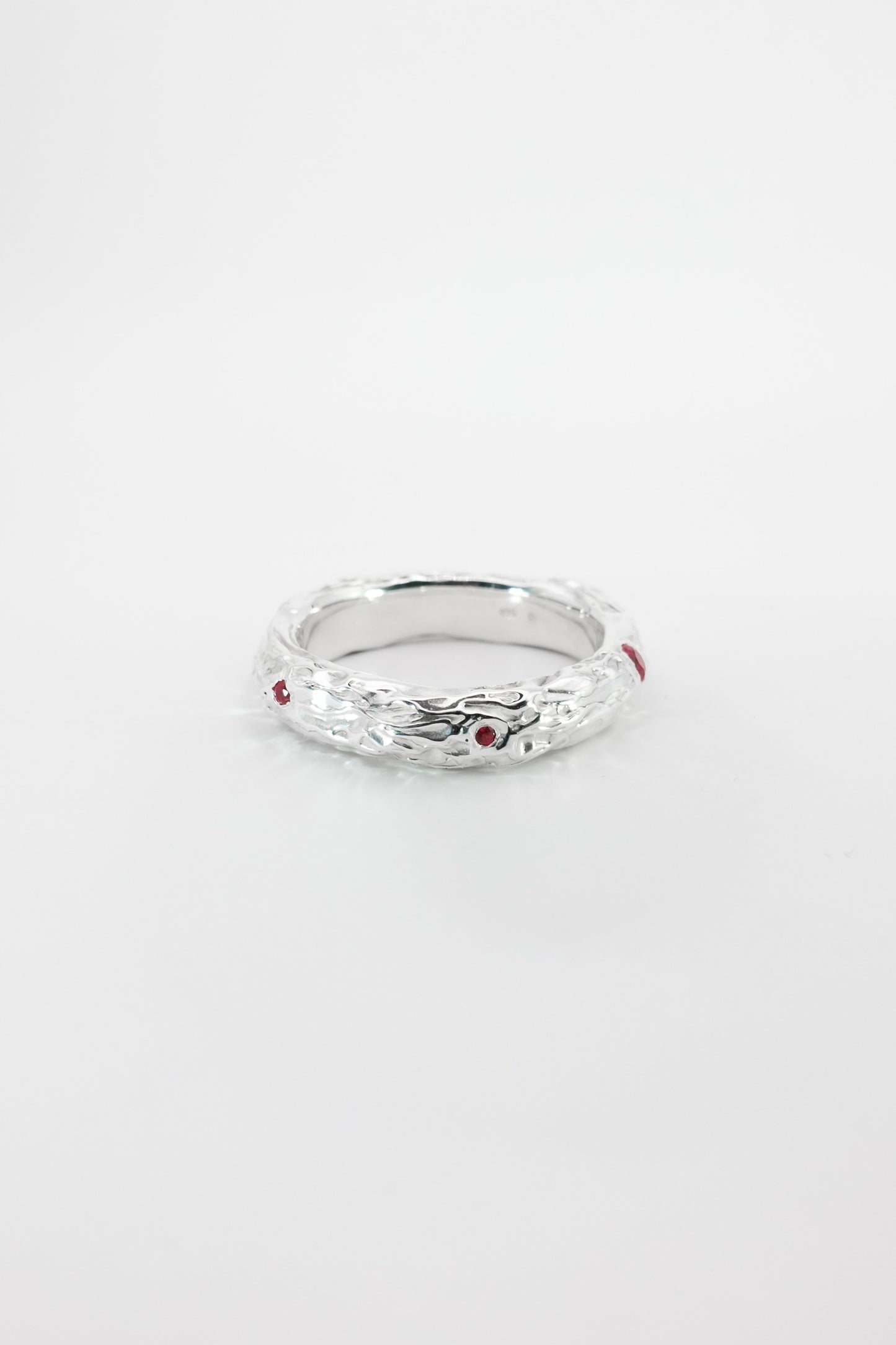 Silver ring with red stones on a white background