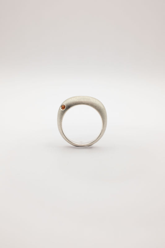 Silver ring with a small brown stone on a light gray background