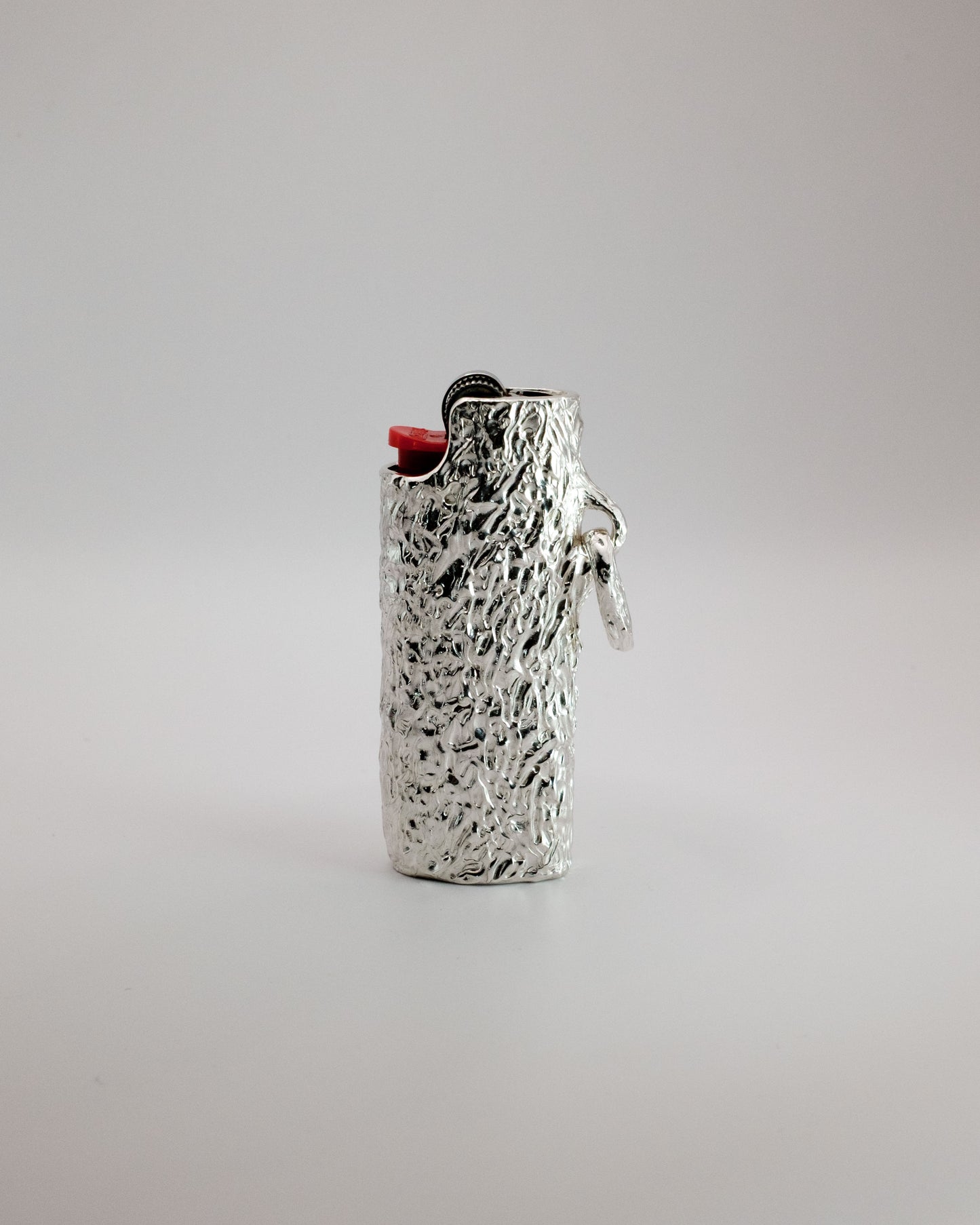Silver textured Bic lighter on a light gray background