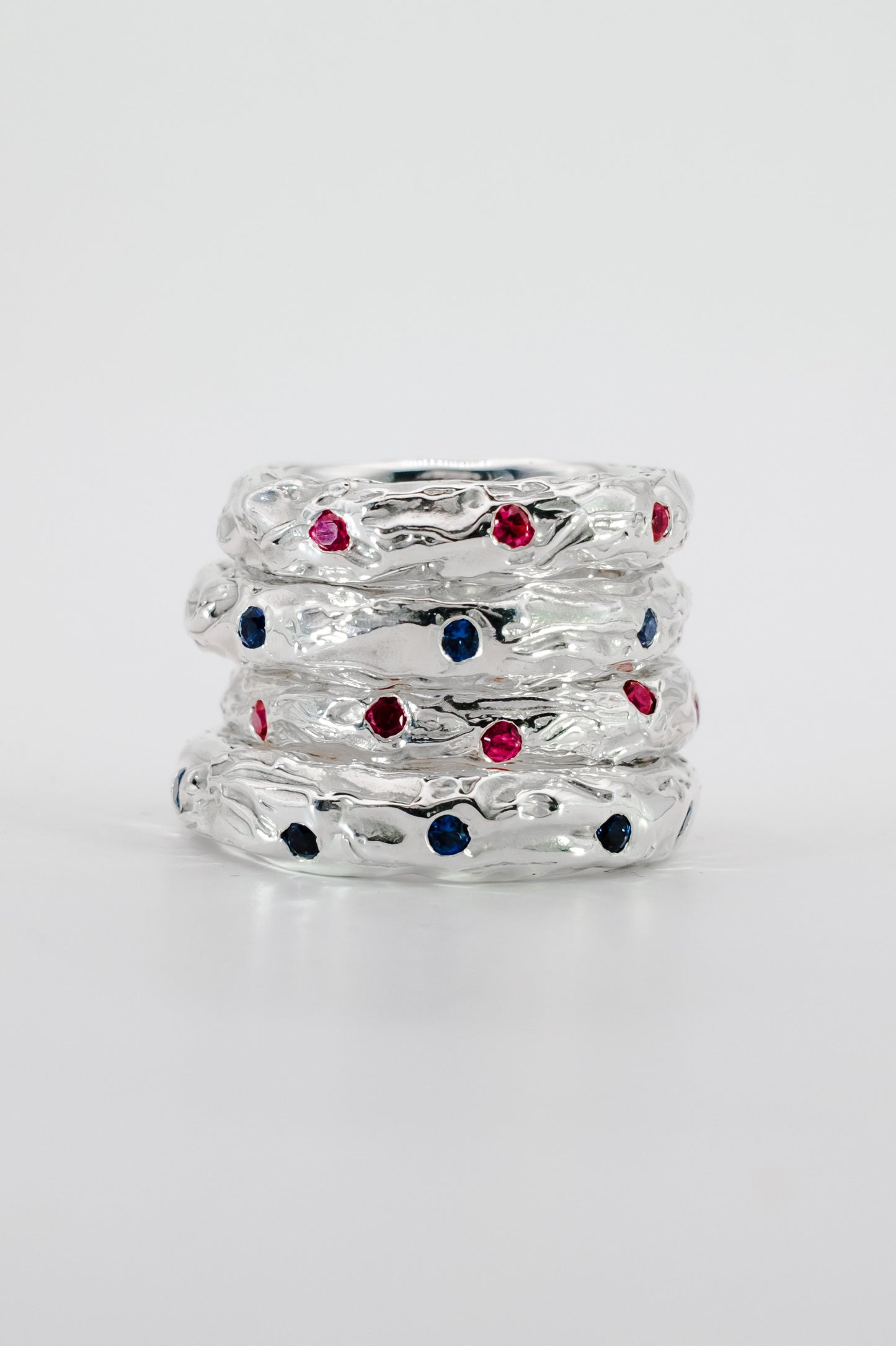 Stack of silver rings with colorful gemstones on a white background