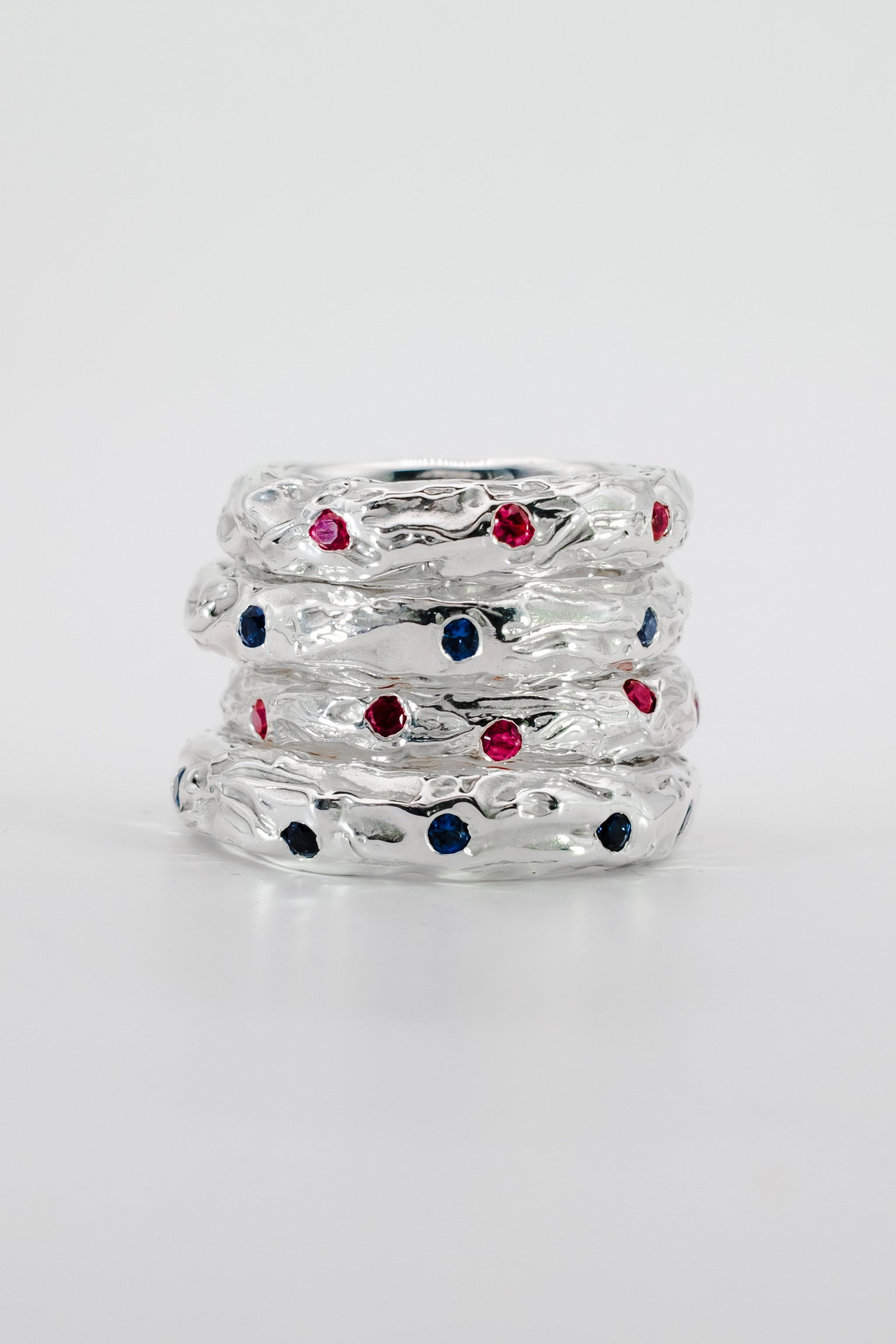 Stack of silver rings with colorful gemstones on a white background